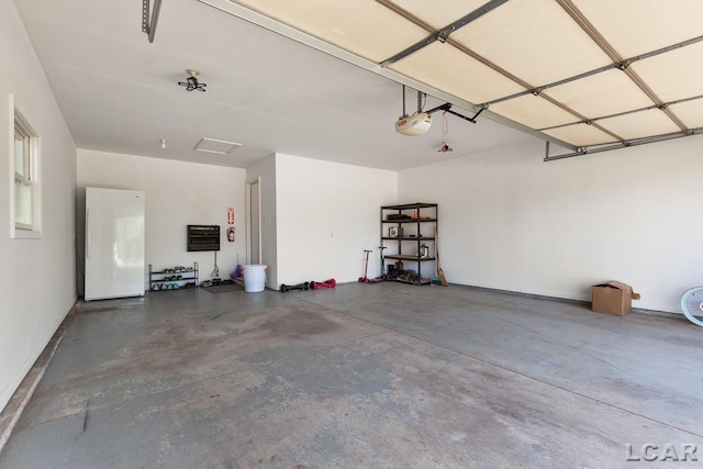 garage featuring a garage door opener and freestanding refrigerator