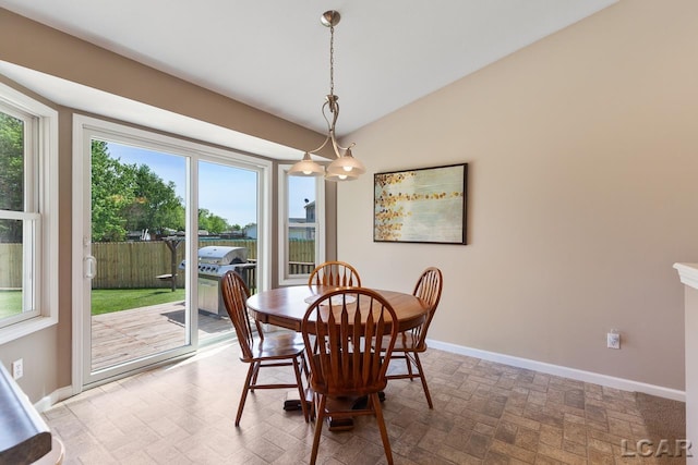 dining space featuring brick floor, baseboards, and vaulted ceiling