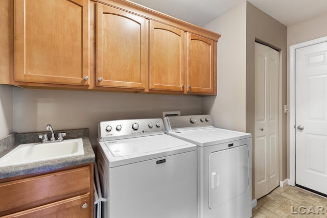 clothes washing area featuring cabinet space, washing machine and dryer, and a sink