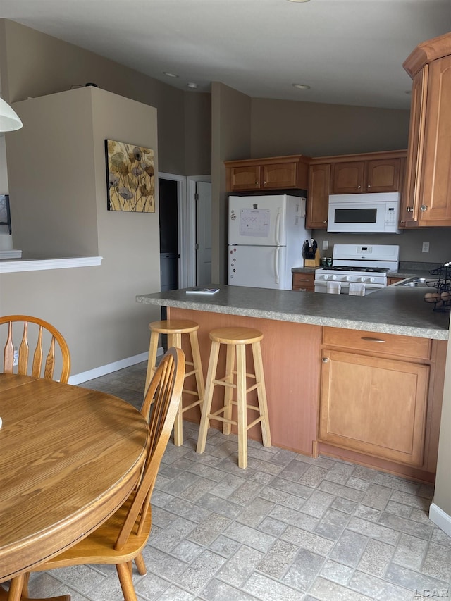 kitchen with a peninsula, white appliances, baseboards, and vaulted ceiling