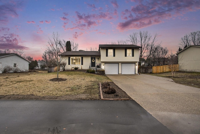 split level home with a garage, driveway, and fence