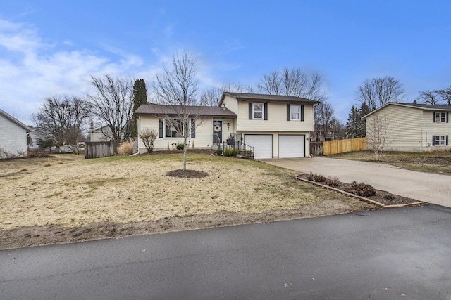 tri-level home with fence, driveway, and an attached garage