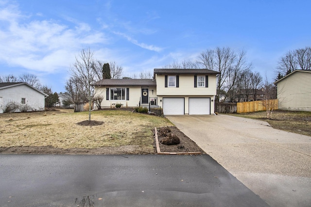 tri-level home featuring fence, driveway, and an attached garage