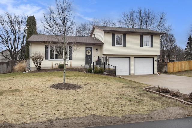 tri-level home with a garage, fence, and driveway