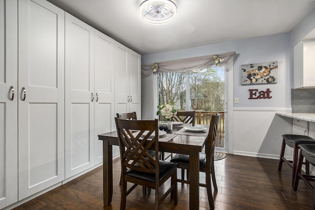 dining room with dark wood-style floors and a wainscoted wall