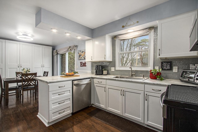 kitchen featuring light countertops, dishwasher, a peninsula, and a sink