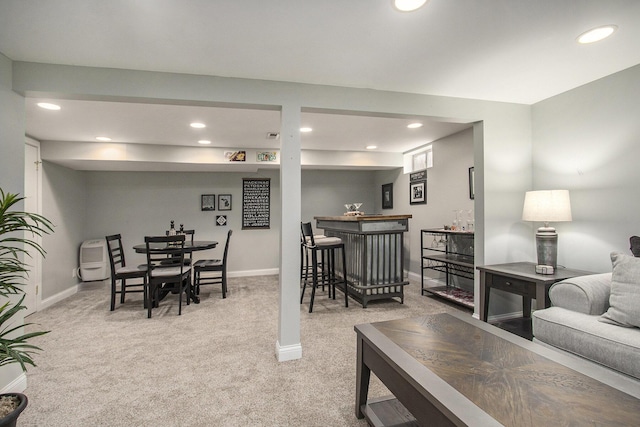 living room featuring baseboards, light colored carpet, and a bar