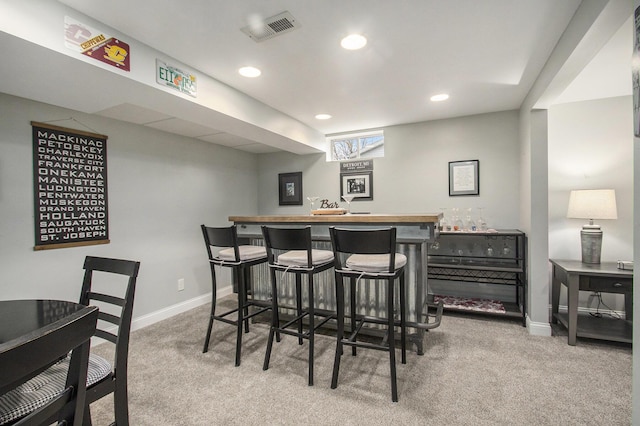 bar with a bar, baseboards, visible vents, and carpet flooring