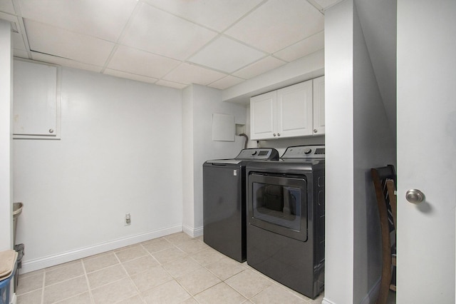 laundry room with light tile patterned floors, separate washer and dryer, cabinet space, and baseboards