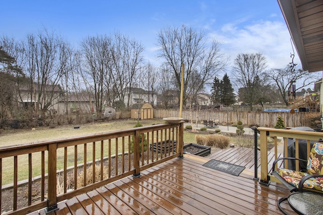 wooden deck with a yard, a fenced backyard, a storage unit, and an outdoor structure