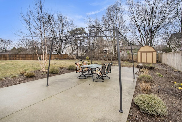 view of patio featuring a shed, outdoor dining area, a fenced backyard, and an outdoor structure