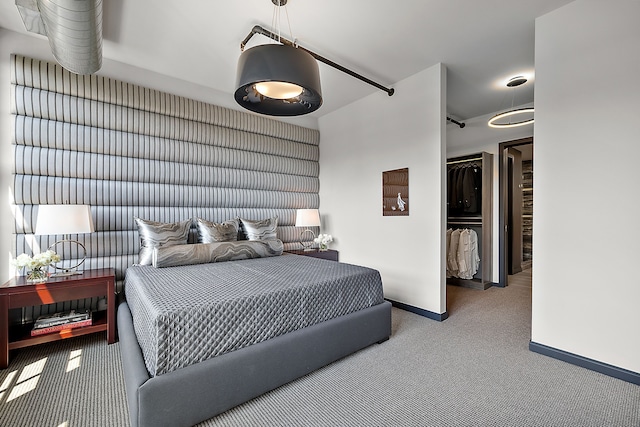 carpeted bedroom with a spacious closet and baseboards