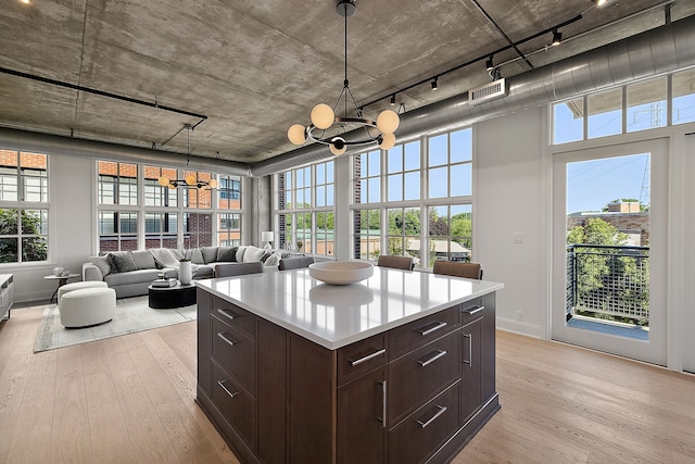 kitchen with light countertops, visible vents, dark brown cabinets, and light wood finished floors