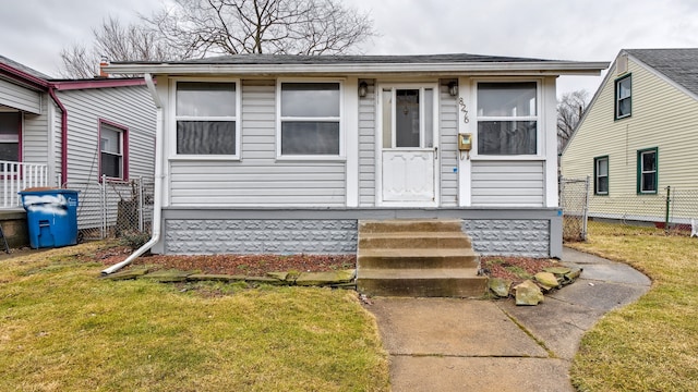 bungalow featuring fence and a front lawn