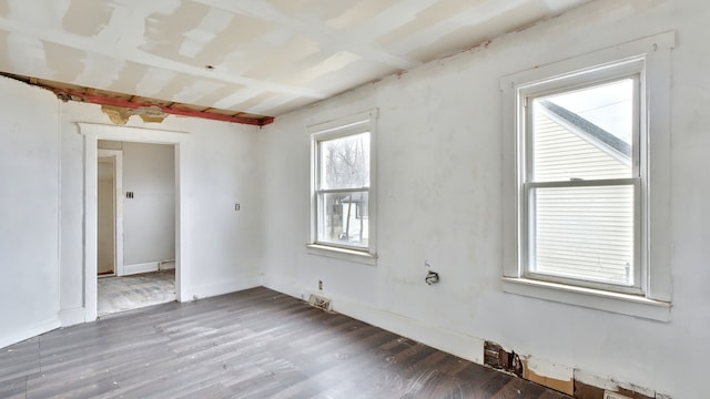 spare room with wood finished floors, visible vents, and baseboards