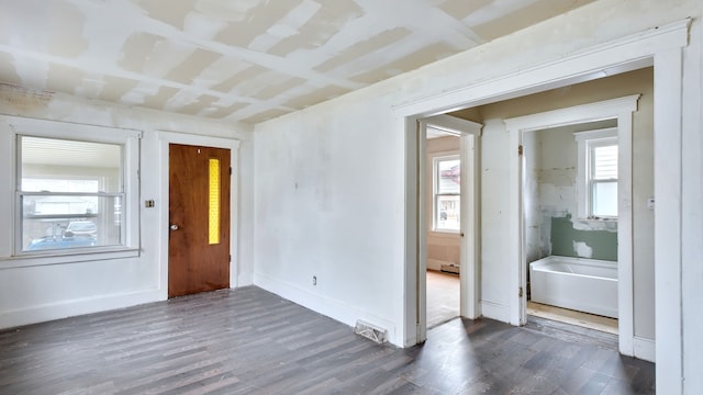 unfurnished room featuring dark wood-style flooring, visible vents, and baseboards