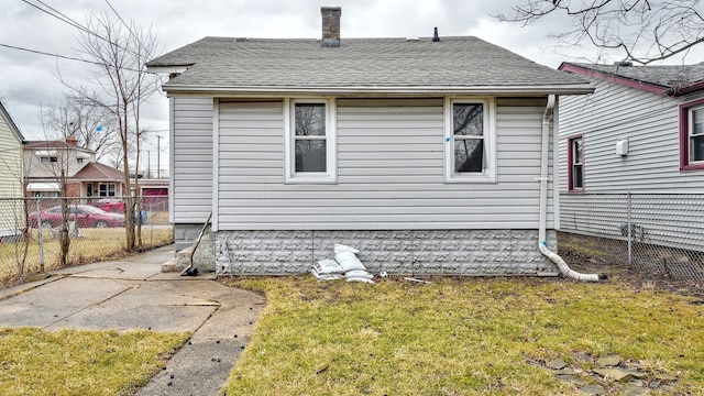 rear view of property with a yard, fence, and a shingled roof