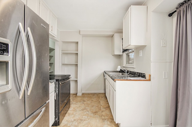 kitchen with dark countertops, freestanding refrigerator, black / electric stove, white cabinetry, and a sink