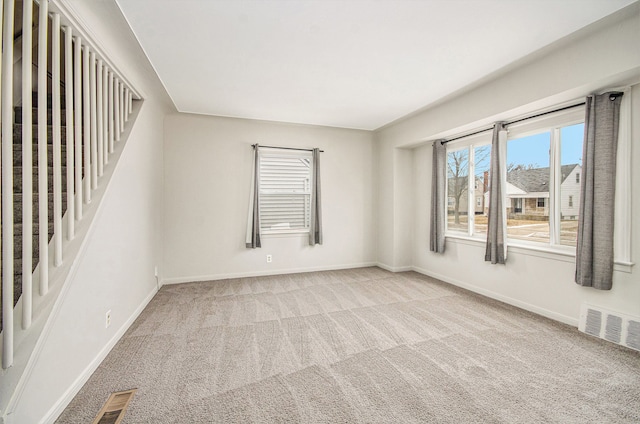 carpeted spare room featuring baseboards and visible vents