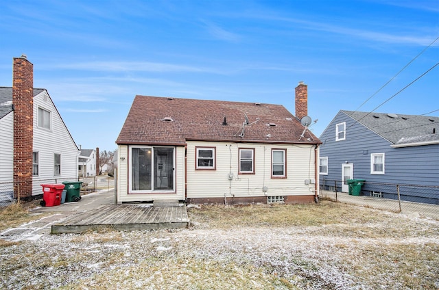 rear view of property featuring a shingled roof, fence, and a wooden deck