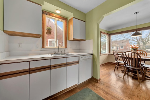 kitchen featuring dishwasher, light countertops, a sink, and white cabinets