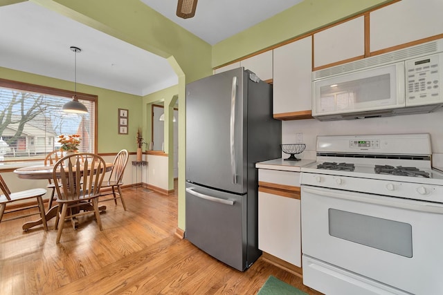 kitchen with decorative light fixtures, light wood finished floors, light countertops, white cabinets, and white appliances