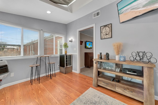 interior space featuring heating unit, light wood-style flooring, visible vents, and baseboards