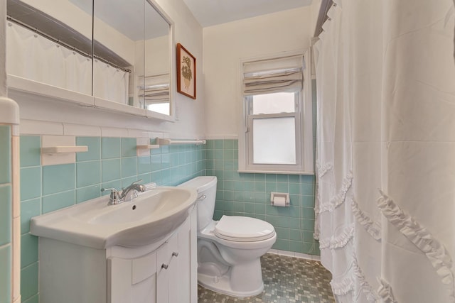 bathroom featuring curtained shower, toilet, a wainscoted wall, vanity, and tile walls