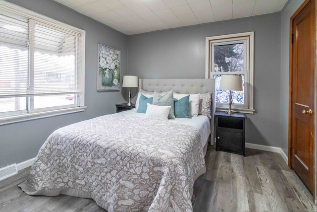 bedroom featuring visible vents, baseboards, and wood finished floors