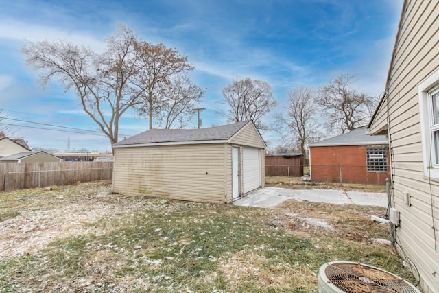 view of yard with a fenced backyard, a detached garage, central AC unit, and an outdoor structure