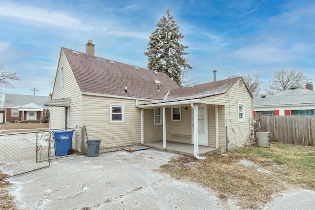 back of property with a shingled roof, a patio area, fence, and a chimney