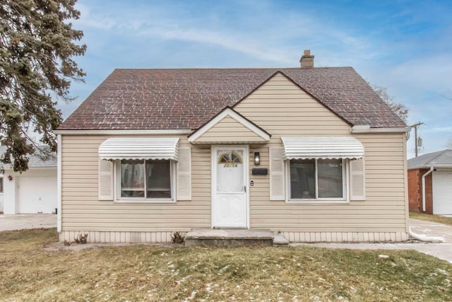 bungalow-style house with a shingled roof, a front yard, and a chimney