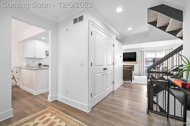 hallway with wood finished floors, visible vents, baseboards, recessed lighting, and stairs