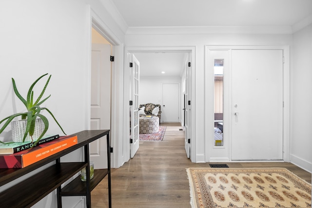 foyer featuring visible vents, wood finished floors, baseboards, and ornamental molding