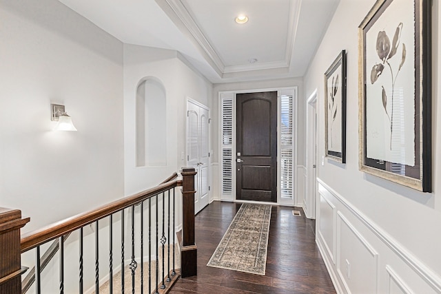 foyer entrance with dark wood-style floors, a tray ceiling, crown molding, a decorative wall, and recessed lighting