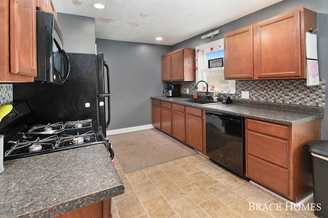 kitchen featuring dark countertops, backsplash, a sink, black appliances, and baseboards