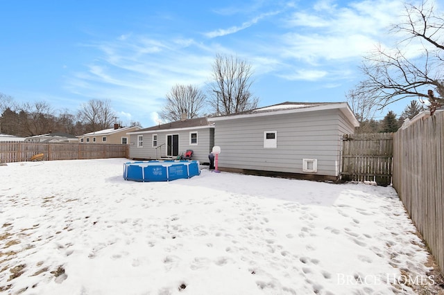 snow covered rear of property with a fenced backyard