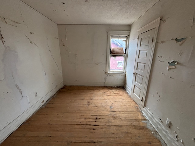 spare room with a textured ceiling and hardwood / wood-style floors