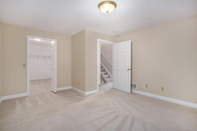 spare room with light carpet, visible vents, and baseboards