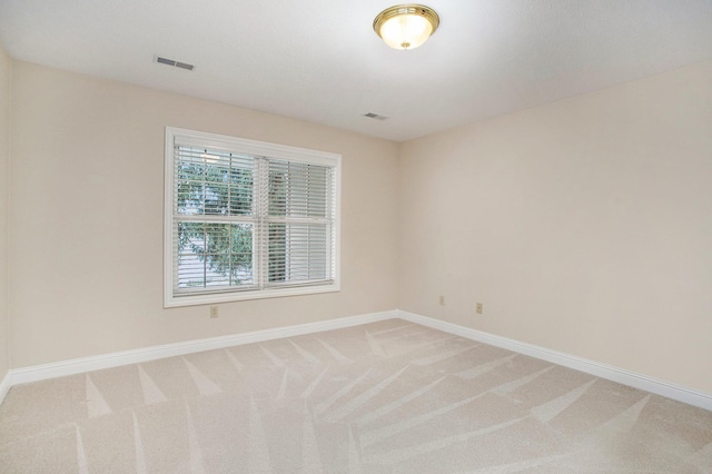 unfurnished room with light colored carpet, visible vents, and baseboards