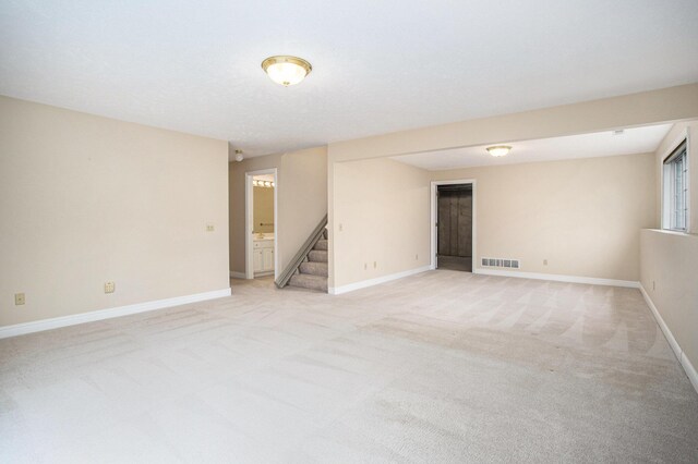 unfurnished room with light carpet, stairway, baseboards, and visible vents