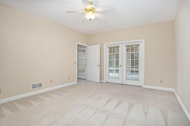 spare room featuring baseboards, french doors, visible vents, and light colored carpet