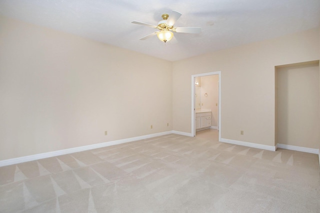 unfurnished bedroom featuring light colored carpet, ceiling fan, ensuite bath, and baseboards