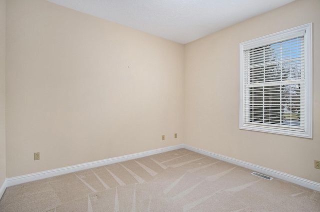 unfurnished room with light colored carpet, visible vents, and baseboards