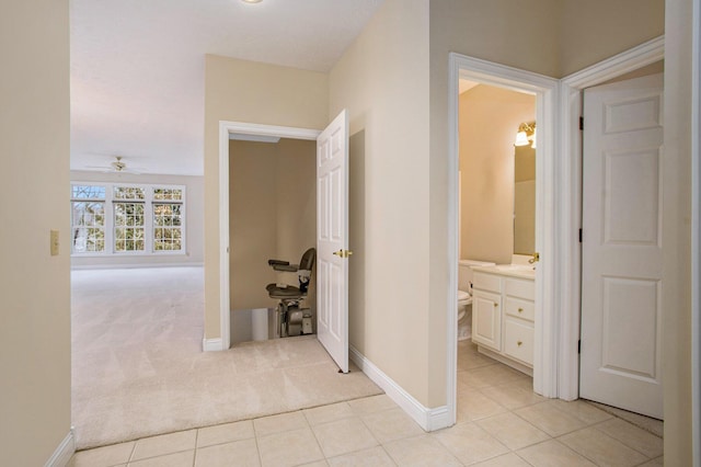 hallway featuring light colored carpet, baseboards, and light tile patterned floors