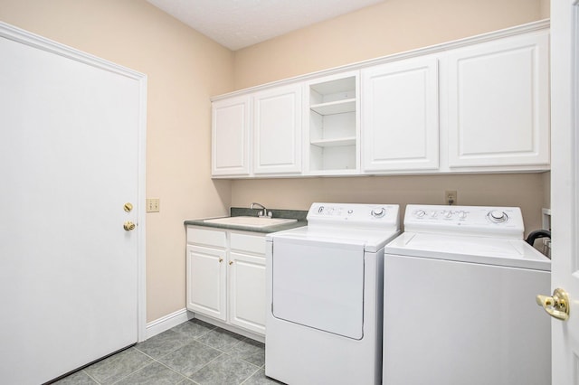 washroom featuring light tile patterned floors, a sink, baseboards, cabinet space, and washing machine and clothes dryer