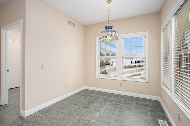 unfurnished dining area with dark tile patterned floors, visible vents, and baseboards