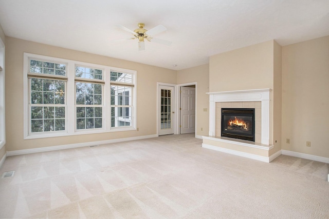 unfurnished living room featuring ceiling fan, light colored carpet, visible vents, baseboards, and a tiled fireplace