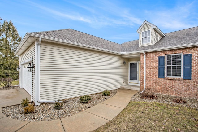 view of front of property with a garage, concrete driveway, roof with shingles, and brick siding