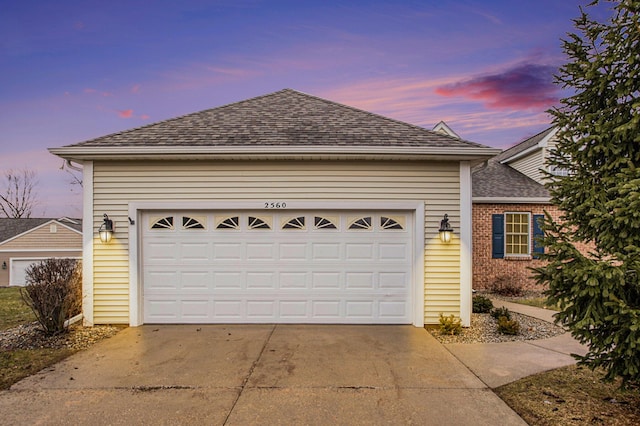 view of front of house with driveway, a shingled roof, a garage, and brick siding